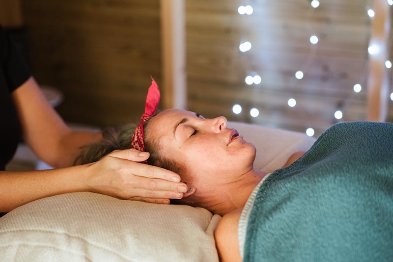 Vrouw op behandeltafel ontvangt Reiki